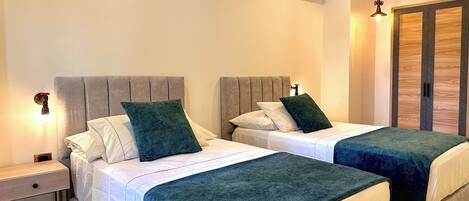 Una habitación de hotel con dos camas, una mesita de noche, un equipo de aire acondicionado y un armario.