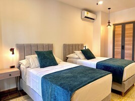 Una habitación de hotel con dos camas, una mesita de noche, un equipo de aire acondicionado y un armario.