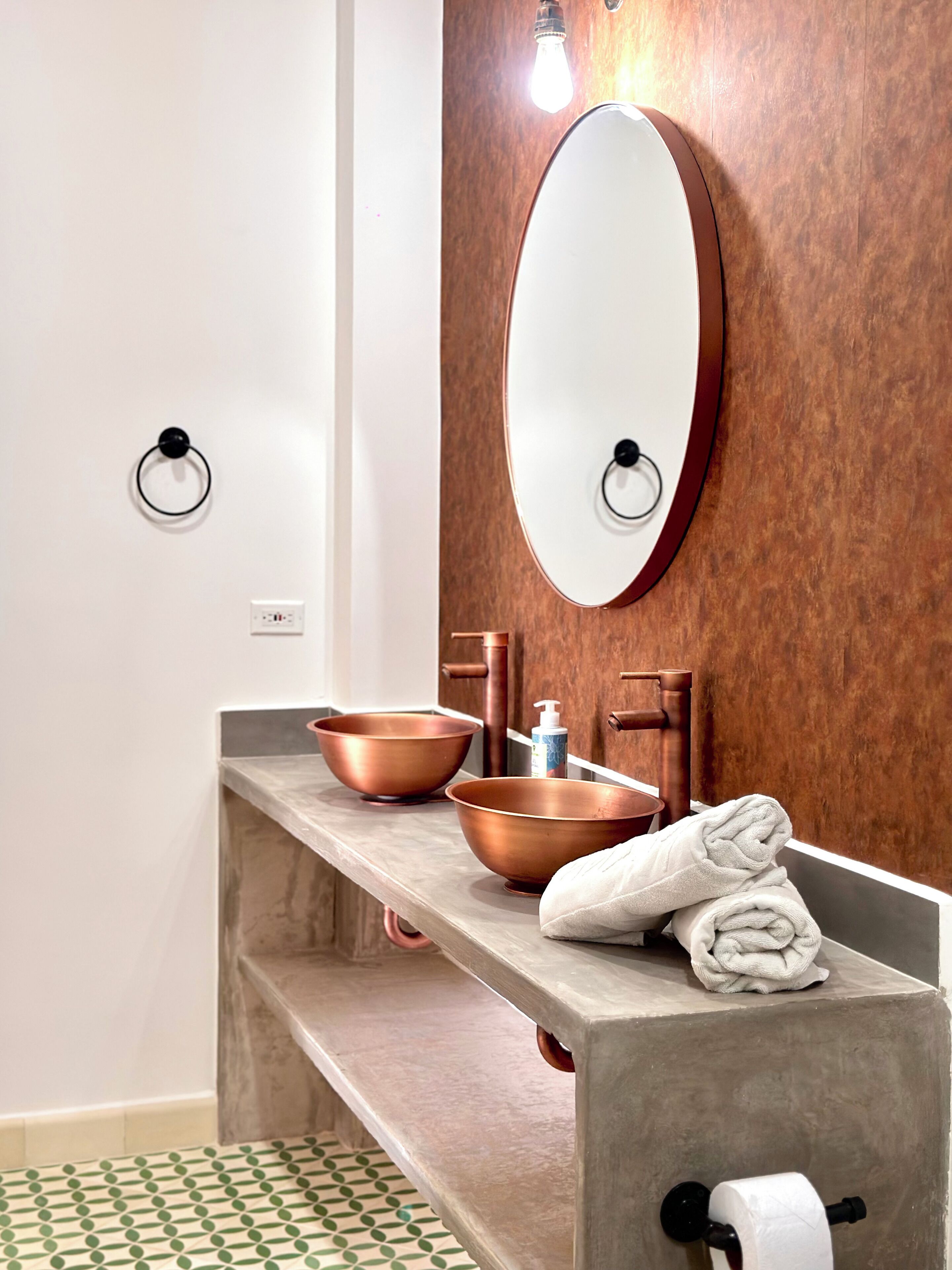 Un bagno con un mobile vanitario in legno, un lavabo in rame e un ampio specchio.