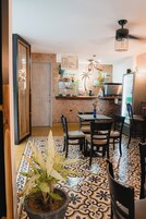 Cocina compacta con área de comedor, suelo de baldosas, planta en maceta y una bicicleta colgada en la pared.