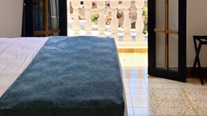 A room with a bed, a balcony door, and a view of buildings. - La Brisa Loca Prime (Santa Marta)