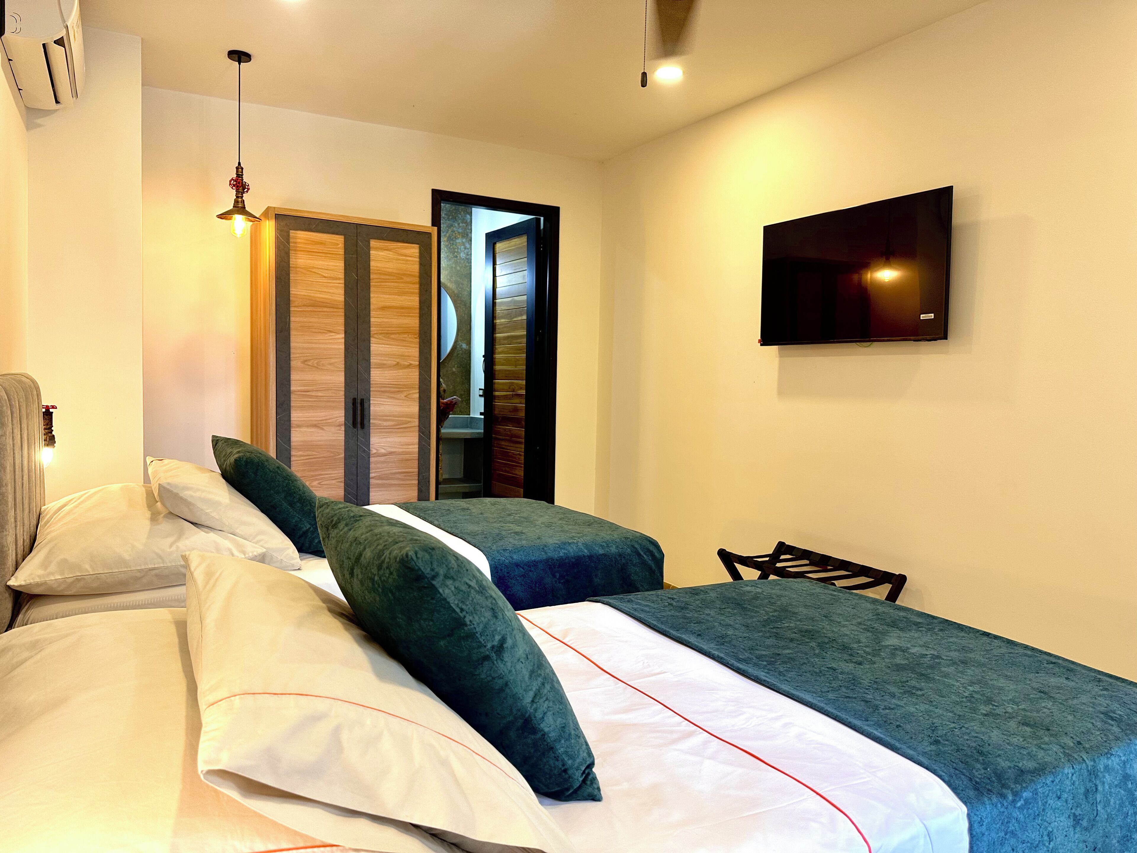 Ein Hotelzimmer mit zwei Betten, einem Fernseher an der Wand und einem Schrank mit Spiegel.