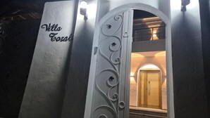 Sisäänkäynti, jossa on koristeellinen metallinen portti ja kyltti, jossa lukee: ”Villa Tozama”.