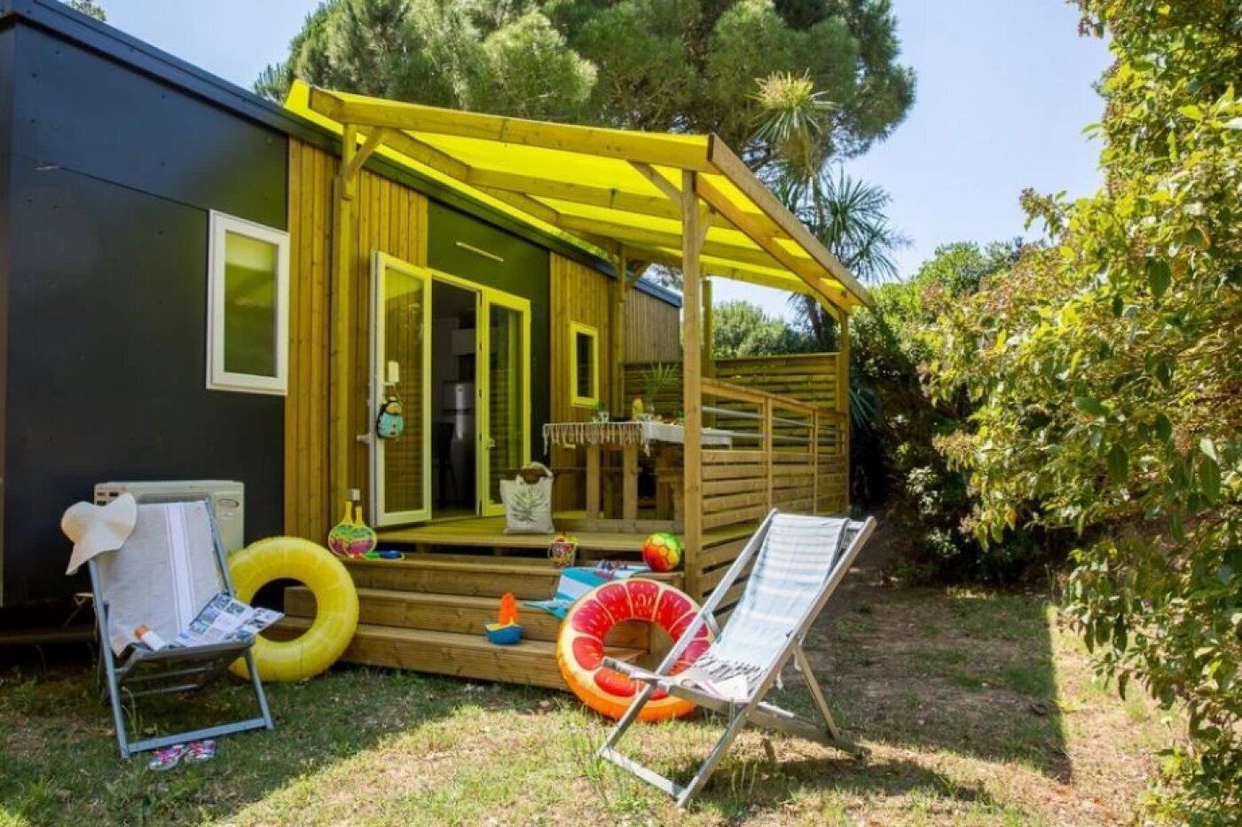 A wooden deck with a yellow pergola, a pool, and a lounge chair.