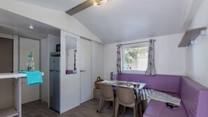 Ein kompakter Wohnraum mit Küchenzeile, Essbereich und einer Sitzecke mit violettem Sofa.