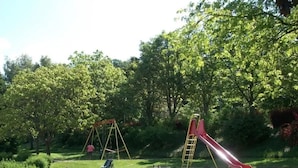 En lekplats med gungor och en rutschkana i en park.