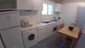 Ett kompakt kök med tvättmaskin, mikrovågsugn och diskho.