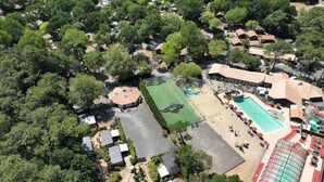Vista aérea de um resort com vários edifícios, uma grande piscina e uma quadra de tênis.