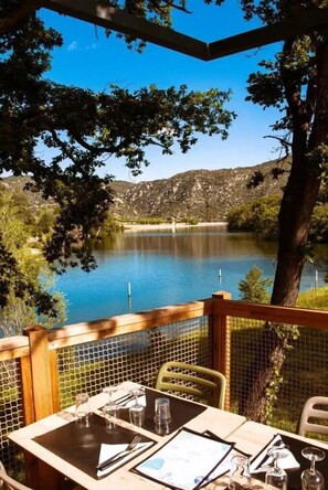 Mesa de comedor al aire libre con vista a un lago y colinas.