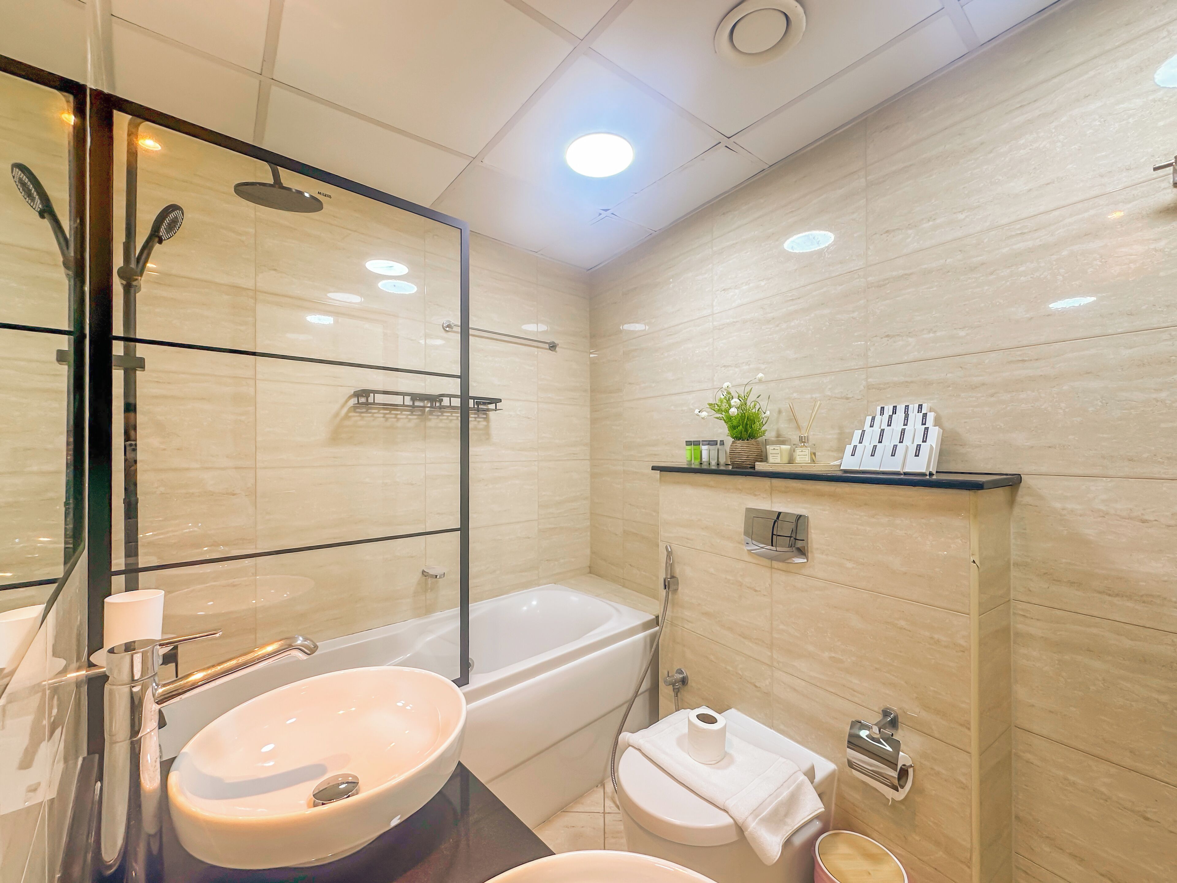 A modern bathroom with a large mirror, two sinks, a bathtub, and a toilet.