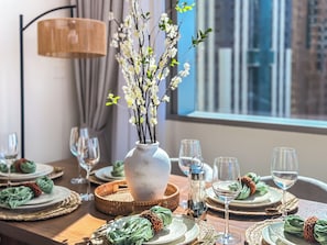 Une table à manger dressée avec des assiettes, des verres et un vase rempli de fleurs.