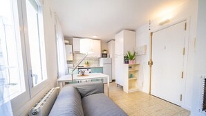 A compact living space with a kitchenette, a sofa, and a radiator. - HomeHolidaysRentals Olimpia - Costa Barcelona (Pineda de Mar)