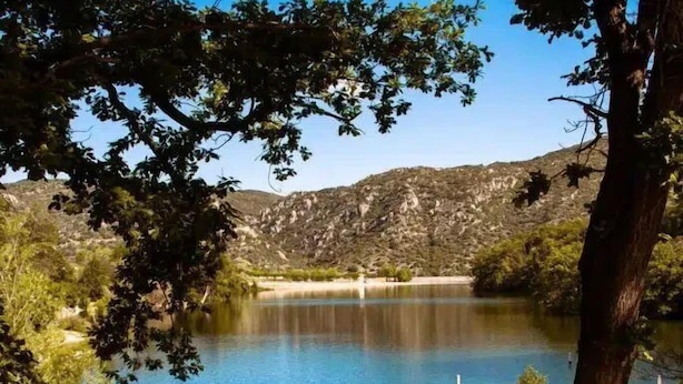 Mesa de comedor al aire libre con vista a un lago y colinas.