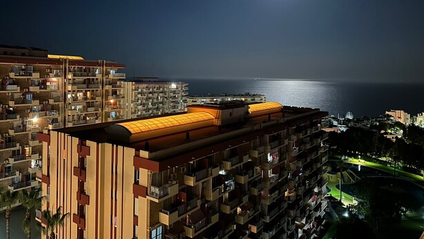 Un edificio de gran altura con varios balcones, una terraza en la azotea y vistas al mar.