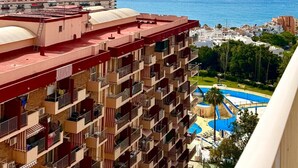 Un hotel moderno de gran altura con varios balcones, piscina y vistas al mar.