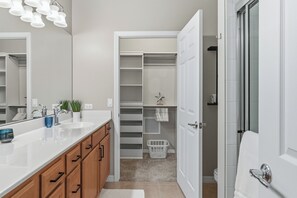 A modern bathroom with a white vanity, a large mirror, and a walk-in closet. - Majestic Palms-Close to Beaches, Heated Pool & Spa, Fully Updated Interior (Fort Myers)