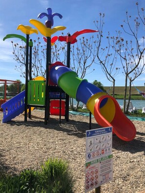 Ein Spielplatz mit Rutsche, Klettergerüsten und Sicherheitshinweisen.