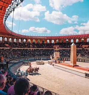 Un estadio amplio, al aire libre, con asientos en niveles y una arena central para eventos.