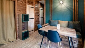 Una stanza accogliente con soffitto in legno, un tavolo da pranzo con sedie, un divano con cuscini e una mensola a muro.