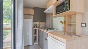 Una cocina compacta con microondas, estufa y refrigerador.