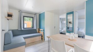 Una habitación moderna y compacta con sofá, mesa de comedor y pequeña cocina.