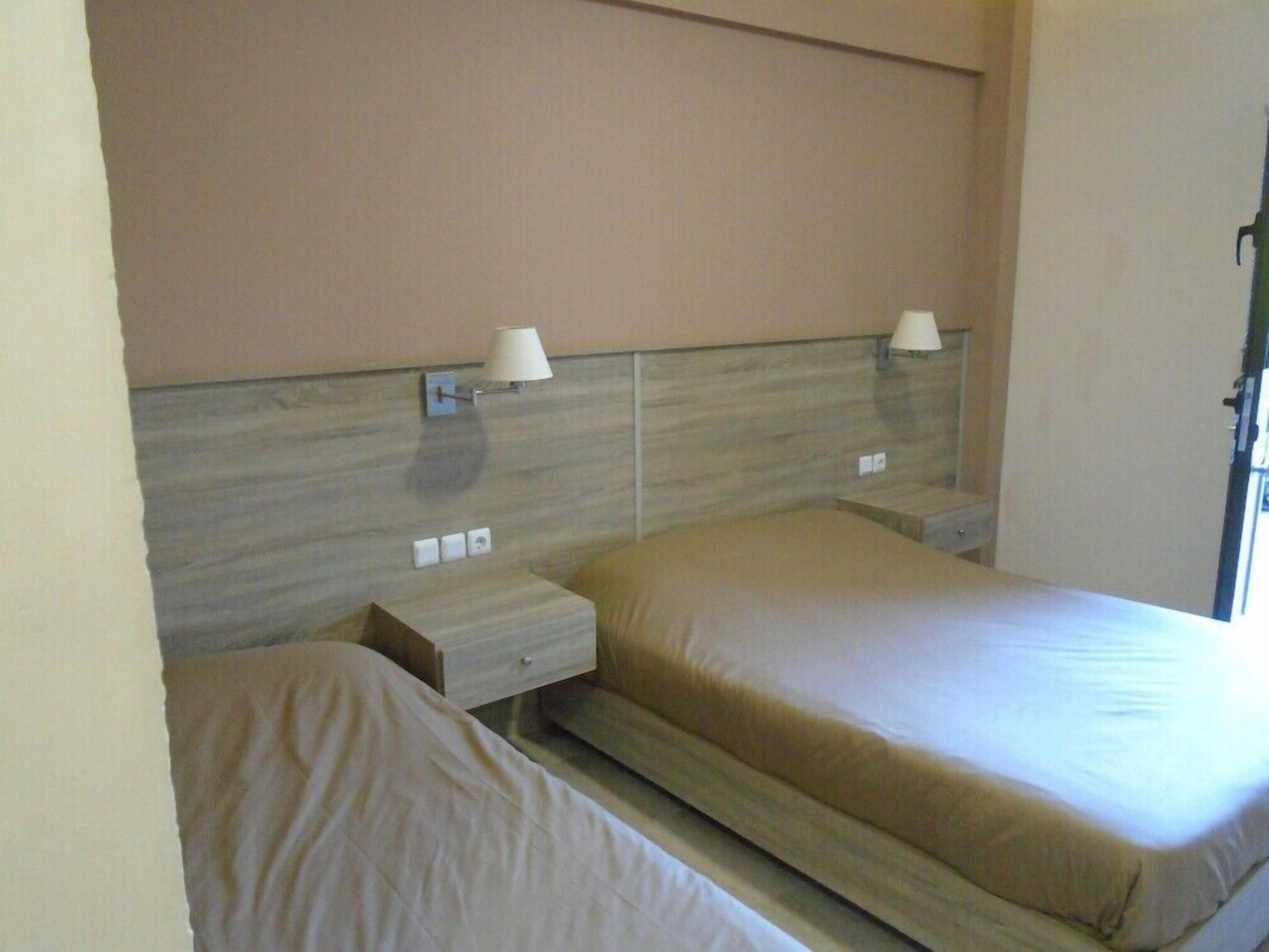 A hotel room with a bed, a nightstand, and a lamp.