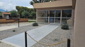 A modern building with a glass entrance, a concrete pathway, and a wooden fence. - Santo George Beach (Malevizi)