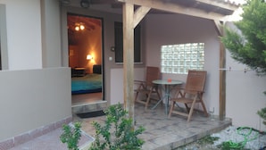 A small patio with a bed, a table, and two chairs. - Santo George Beach (Malevizi)