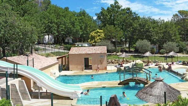 Un área de piscina con tobogán acuático, varias piscinas y zonas de descanso.
