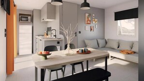 Cocina moderna con microondas, pileta y encimera. Hay una mesa de comedor con sillas y un banco. Un sofá está apoyado contra la pared, sobre él hay una ventana.