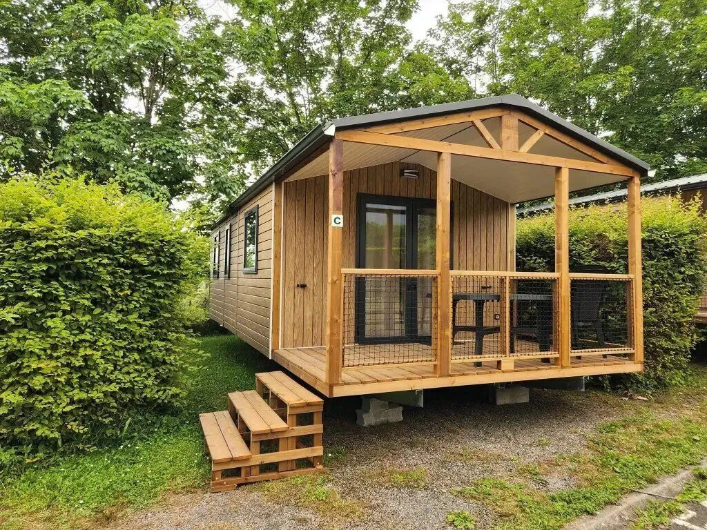 Een houten hut met een overdekte veranda, een deur en een raam.
