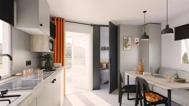 A modern kitchen with a dining area, a view of the outdoors, and a small seating space. - ZEcamping 3* animaux acceptés locatif TV clim 23m2 4 pers (Divonne les Bains)