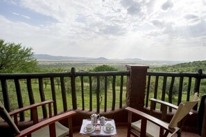 Un balcon avec une table dressée pour le thé, d’où l’on peut admirer un paysage de savane avec des montagnes à l’horizon.