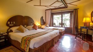 A hotel room with two beds, a wooden headboard, a desk with a lamp, and a window with curtains. - Serengeti Serena Safari Lodge (Serengeti)
