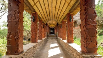 Un pasillo con escalones de piedra que conducen a una puerta, flanqueado por columnas ricamente talladas.