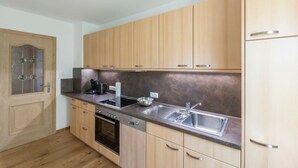 A modern kitchen with wooden cabinets, a stainless steel sink, and a built-in oven. - Zwei Appartements im EG fur Befreundete Familien (Grainau)