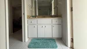 A bathroom with white cabinets, a sink, and a mirror.