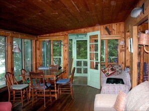 L’intérieur d’un chalet en bois comprend un coin repas, un canapé et une porte donnant sur l’extérieur.