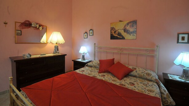 Une chambre à coucher avec un lit, une commode, une table de chevet, une lampe et un tableau au mur.