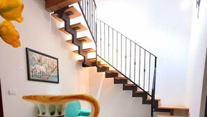 Un intérieur moderne avec un escalier, un vase décoratif et un tableau encadré au mur.