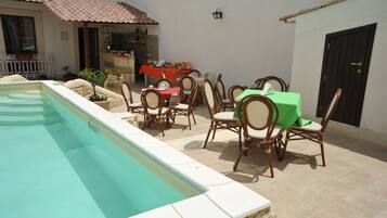 Area piscina con zona pranzo completa di sedie e tavoli, angolo cottura e una porta.