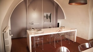 A modern kitchen with a white countertop, clear chairs, and a hanging light fixture. - B B La Casa Del Poeta (Enna)