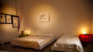 A room with two beds, a small table, a wall with framed papers, and a green rug. - B B La Casa Del Poeta (Enna)