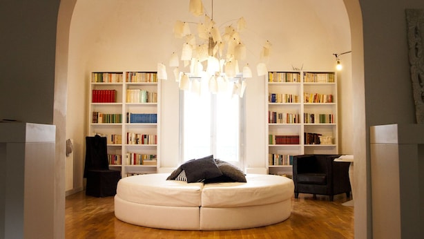 A circular seating area with a white sofa, a chandelier, and bookshelves in the background. - B B La Casa Del Poeta (Enna)