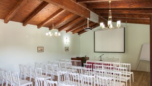A conference room with white chairs, a projector, a screen, and a podium. - Villa Giuliana (Licata)