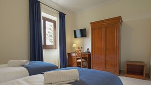 A hotel room with two beds, a desk, a TV, and a wardrobe. - Villa Giuliana (Licata)