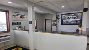 Un espace d’accueil avec un comptoir, une affiche encadrée sur les courses de chevaux, un panneau d’accueil et une plante posée sur le comptoir.
