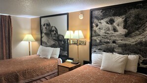 Une chambre d’hôtel avec deux lits, un grand tableau encadré au mur, deux lampes de chevet et une table de chevet avec une lampe.