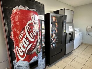 Una máquina expendedora con un rótulo de Coca-Cola Classic, un dispensador de botellas de agua y un refrigerador.