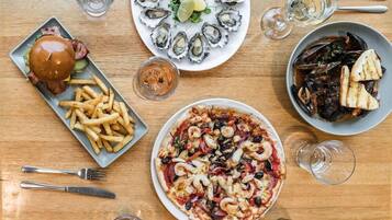 A dining table with various dishes including seafood, a burger, and fries, along with cutlery and glasses.